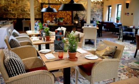 Comfortable whicker dining chairs, a patchwork tiled floor and statement lighting create an eclectic dining space at The Swan Hotel