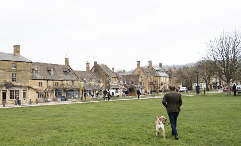 Man walking his dog across the green towards Broadway village centre