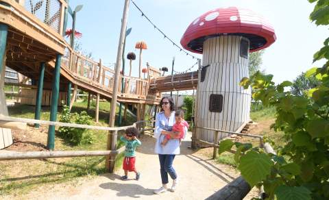 A mother and two children walk through a play area of giant toadstools at Fairytale Farm