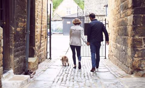 A couple walking a dog outside the Lygon Arms Hotel