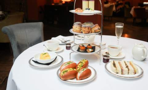An afternoon tea of sandwiches, rolls, scones and delicate cakes, as well as glasses of champagne, at The Kings Head Restaurant in the Cotswolds