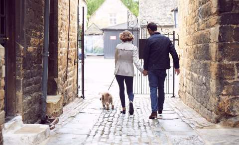 A couple walking a dog outside the Lygon Arms Hotel
