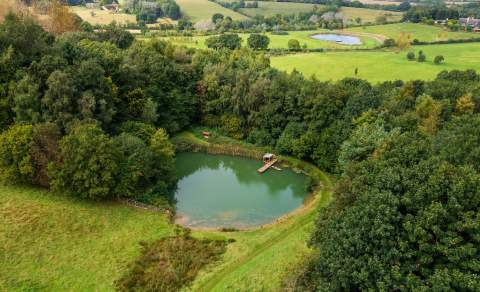 The spring-fed lake at Heath Farm Holiday Cottages surrounded by woodland and open fields