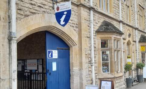 Large wooden gates painted blue in a Cotswold stone building, mark the entrance to the Visitor Information Centre in Chipping Campden