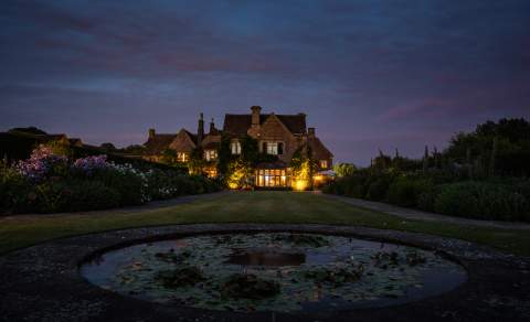 Lights glow from Whatley Manor as dusk sets in