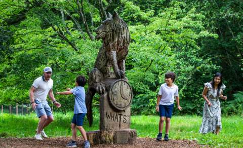 Family playing around wooden statue at Westonbirt Arboretum