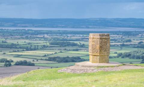 View from Nympsfield Long Barrow looking down from the Cotswold escarpment towards the River Severn and the Welsh mountains