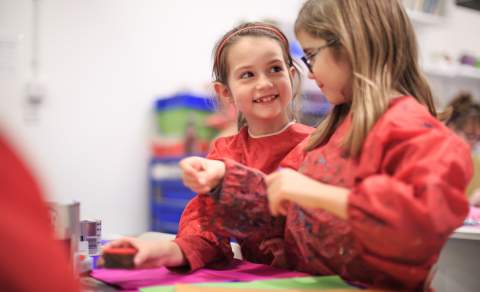 Children in aprons enjoying painting