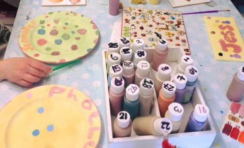 Table laid with lots of pottery activities and children enjoying them