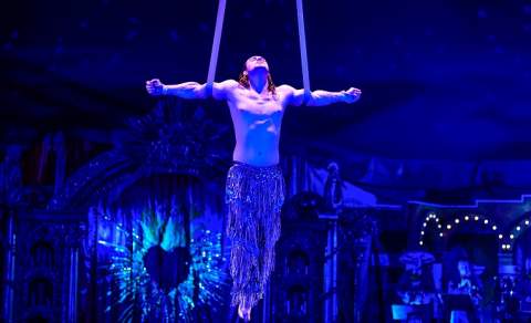 An aerial performer hangs from ribbons from the ceiling