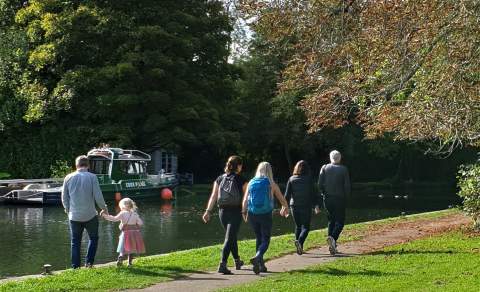 People walking along the Thames Path along the river.