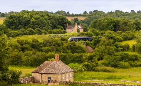 A view of North Leigh Roman Villa with a GWR train passing in the distance behind