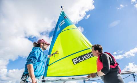 two men in front of a sailing boat