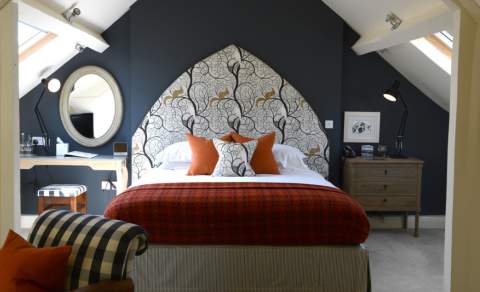 Bedroom at The Close Hotel in Tetbury with dark blue wall and elaborate headboard