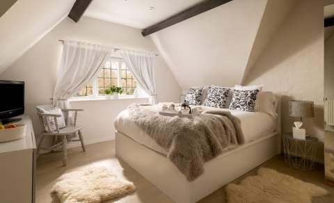 Bedroom in cottage with furry bedspread and wooden beams