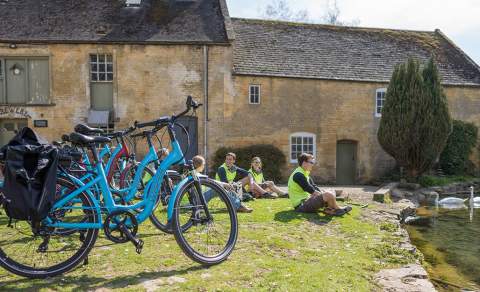 A group of cyclists sitting by a pond