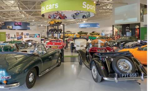 A myriad of classic cars gleam under bright lights in the British Motor Museum