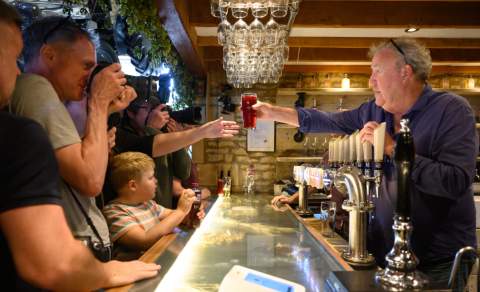 Jeremy Clarkson passes a pint to a customer at his busy bar at The Farmer's Dog