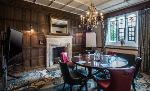 A small meeting room with wood paneled walls and chandeliers at Ellenborough Park