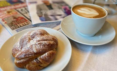 En kaffekopp og en bolle på ett bord