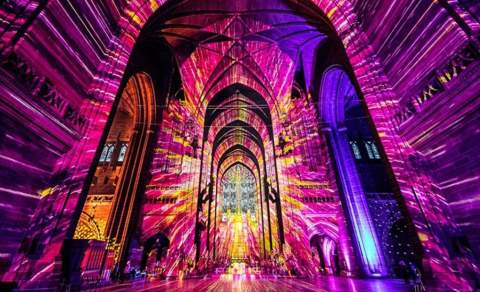 Purple and yellow light fills the interior of Tewkesbury Cathedral in the Cotswolds