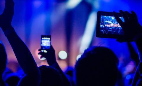 A crowd waving their arms at a concert in East Yorkshire whilst filming the act on stage on their mobile phones