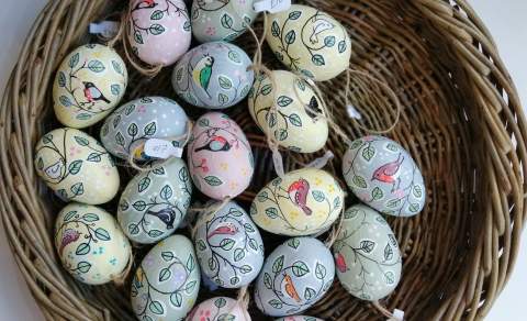 A wicker basket filled with pastel-coloured handpainted eggs from The Gloucester Guild of Craftsman