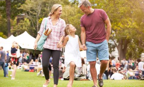 A family at a festival. a woman and a man with a young girl between them.