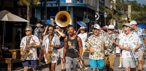 A group of musicians walking down Dauphin Street in downtown Mobile.