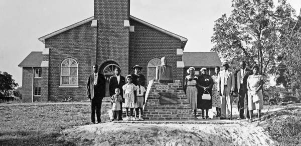 black and white photo of a group of people standing in front of a church