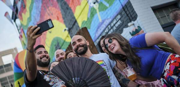 group of people taking a selfie in front of a rainbow mural