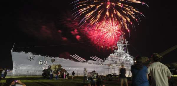 Red fireworks explode at night above the USS ALABAMA battleship