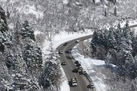 Cars driving on a slightly wet road in a snowy canyon