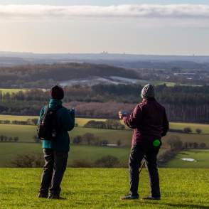 two people stood on a hill with rolling fields in background