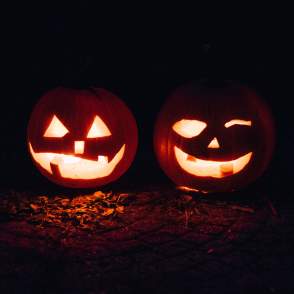 Two jack-o-lanterns glow in candlelight on an October night.