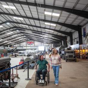 two people in a hanger with aviation props and planes in background