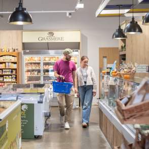 two people in farm shop with basket in hand surrounded by local produce