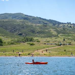 Kayaker and people recreating in background of a cove in Horsetooth Reservoir.