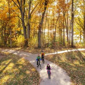 Family bikes on the B2B trail during fall on a dirt pathway with treelined background