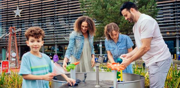 Family playing with an outdoor water feature in birmingham