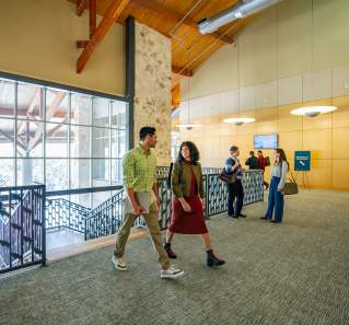 Image of a group of people dressed in business casual walking into the Palmer Events Center and chatting with one another.