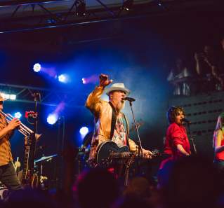 Image of a band onstage at Mohawk with the main man holding his hand up and singing into the microphone.