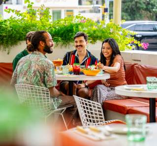 Image of a group of men and women sitting at a table smiling at one another on the patio at Joann's.