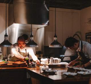 Chefs plating up dishes in what looks like a home kitchen at the Pasta Bar Austin experience.