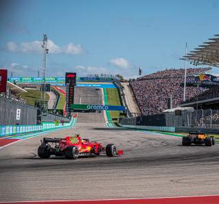 Two formula one cars round the turn in front of fan stands at Austins Circuit of The Americas racetrack