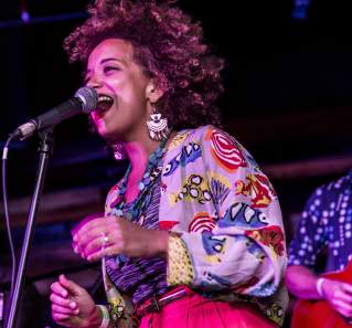 KP & The Boom Boom singer on stage with a guitarist playing behind her