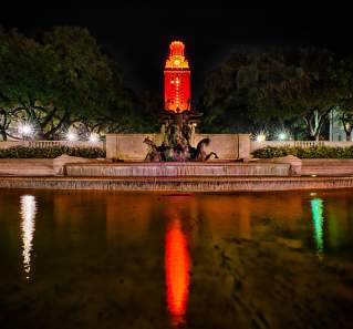 The University of Texas fountain and Tower lit up orange in Austin Texas