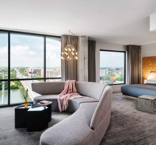 Large, modern hotel room with floor to ceiling windows overlooking Congress Avenue Bridge.
