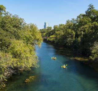 Two kayakers paddling through the Barton Creek Greenbelt in austin texas