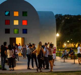 Groups of people gathering outside of Austin at the Blanton Museum at night.